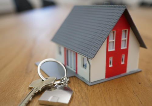 Schlüssel auf einem Tisch vor einem Haus-Modell
